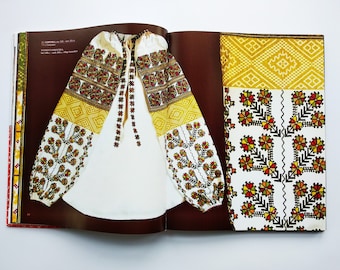 Può includere: Una blusa bianca ricamata con motivi floreali gialli, rossi e neri. La blusa è aperta per mostrare i dettagli intricati del ricamo. L'immagine mostra anche un primo piano dei motivi di ricamo.