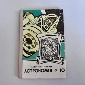 Può includere: Libro di testo di astronomia vintage con dorso rosa chiaro. La copertina presenta illustrazioni di un telescopio e di un astrolabio, con il titolo "ASTRONOMIA" in grassetto. Lo sfondo è un mix di verde acqua, bianco e nero.