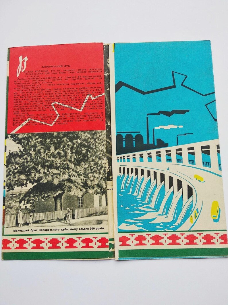 May include: Open book with a red and blue cover. The left page has text and a black and white image of a tree and people. The right page has a blue illustration of a dam and factories. The bottom border has a red and green pattern.