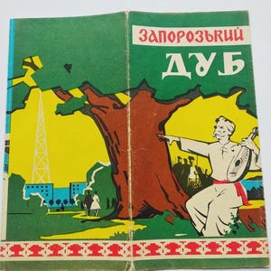 May include: Vintage book cover featuring a colorful illustration. The cover displays the title "Zaporozhskyi Dub" in red and white text. The artwork depicts a tree, a man playing a stringed instrument, and a landscape with buildings and a tower.