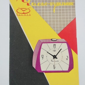 Puede incluir: Un anuncio vintage con un despertador morado y blanco. El reloj tiene una esfera cuadrada con manecillas y números negros. El fondo incluye formas geométricas amarillas, negras, grises y rojas, texto cirílico y la palabra "Vityaz".