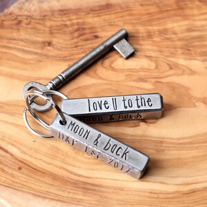 May include: Two silver metal keychains with engraved messages. The top keychain says "love U to the moon & back". The bottom keychain says "Moon & back D&F Est. 2017".