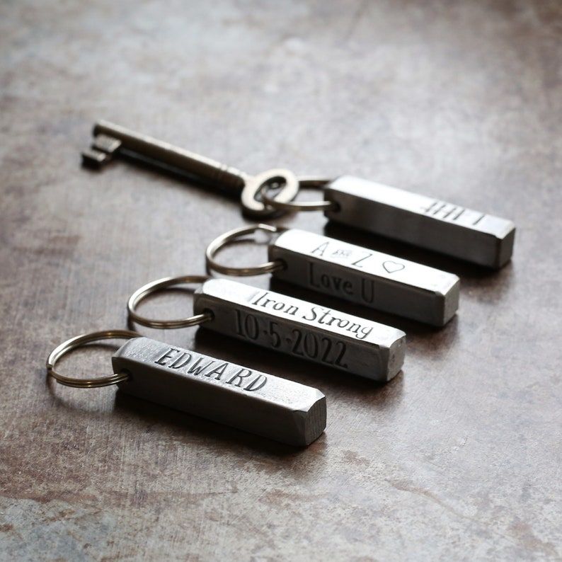 May include: Four silver keychains with engraved messages. The keychains feature a silver bar with the following text: "A is Z Love U", "Iron Strong 10-5-2022", and "EDWARD".
