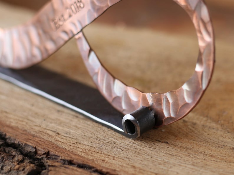 May include: Close-up of a copper bottle opener with a textured surface and a dark metal handle. The text "Est. 2018" is stamped on the copper. The opener is on a wooden surface.