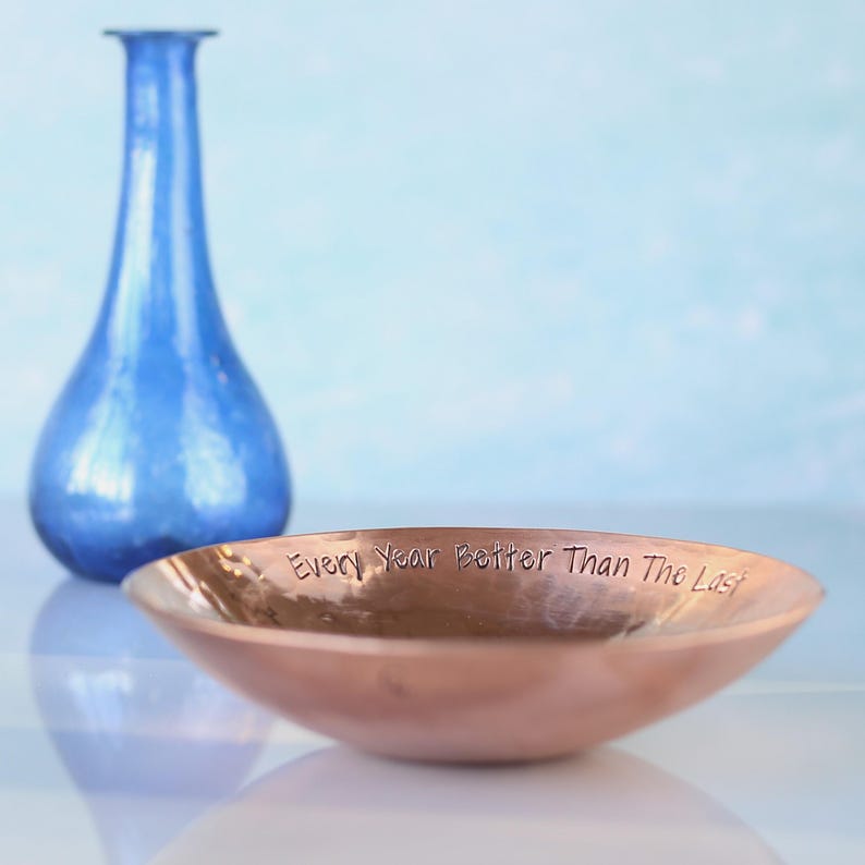 May include: A copper bowl with a hammered finish and the inscription "Every Year Better Than The Last" on the rim.