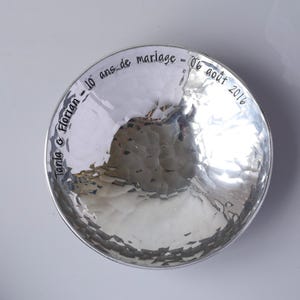 May include: A round, silver-coloured bowl with a hammered, reflective surface. The inner rim features black engraved text that reads: Tania & Florian - 10 ans de mariage - 06 ao&ucirc;t 2016. The bowl has a smooth, polished finish and a circular shape.