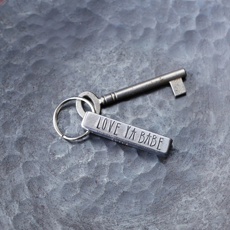 May include: A silver key chain with a silver key and a silver tag that says "LOVE YA BABE".