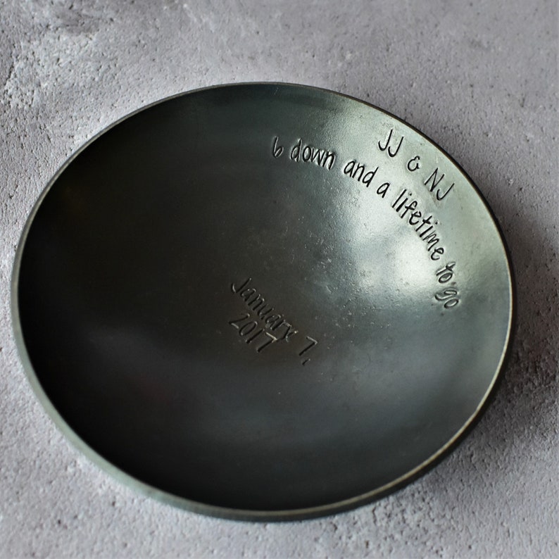 May include: A dark gray metal bowl with the inscription "JJ & NJ 6 down and a lifetime to go January 1, 2017".