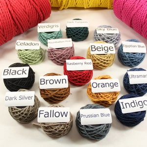 May include: A collection of 16 balls of cotton cord in various colors, including black, brown, orange, beige, red, blue, green, and gray. Each ball has a white label with the color name printed on it.
