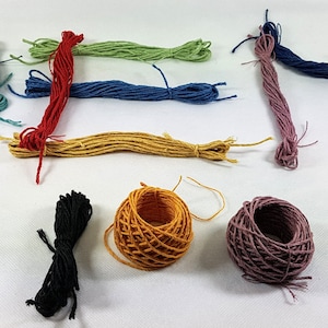 May include: Assortment of embroidery floss in various colors, including green, blue, red, yellow, orange, and gray. There are also three spools of floss in black, orange, and purple.