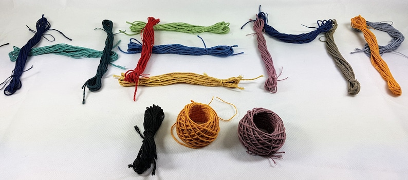 May include: Assortment of embroidery floss in various colors, including green, blue, red, yellow, orange, and gray. There are also three spools of floss in black, orange, and purple.