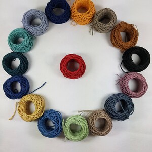 May include: A collection of 15 spools of colorful string arranged in a circle. The spools are in various shades of blue, green, red, yellow, brown, and pink.
