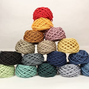 May include: A pyramid of yarn balls in various colors, including red, yellow, brown, gray, blue, and green. The yarn balls are arranged in a triangular shape, with the largest ball at the top and the smallest balls at the bottom.
