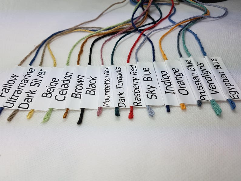 May include: A collection of embroidery floss spools in various colors, including fallow, ultramarine, dark silver, beige, celadon, brown, black, Mountbatten pink, dark turquoise, raspberry red, sky blue, indigo, orange, Prussian blue, verdigris, and Egyptian blue.