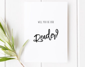 May include: White card with black text that reads "Will you be our Reader?"  The card is on a white wood background with a small green sprig.