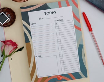May include: A colorful daily planner pad with the word "TODAY" at the top. The pad features sections for to-do lists, schedules, and notes, with a design of teal, orange, and gold arches. A red pen rests on the side.