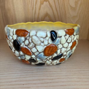 May include: A white ceramic mug with a black handle and the text "But First, Coffee" in a black, bold font. The mug is on a white surface.