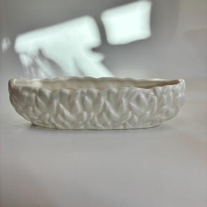 May include: A set of three ceramic mugs with a speckled, matte finish in cream, light grey, and dark grey. Each mug has a simple, modern design and a rounded handle.