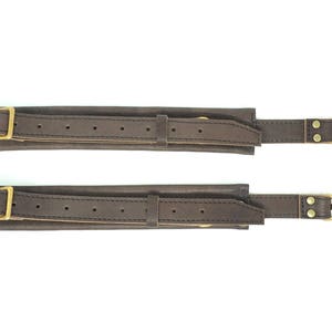 May include: Two brown leather straps with gold metal buckles and clasps. Each strap has a series of small holes for adjusting the length.