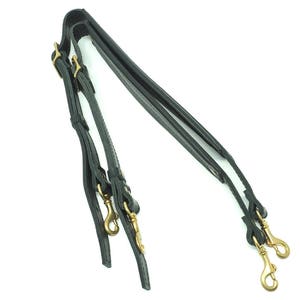 May include: A pair of black leather shoulder straps with gold metal clasps and hooks.