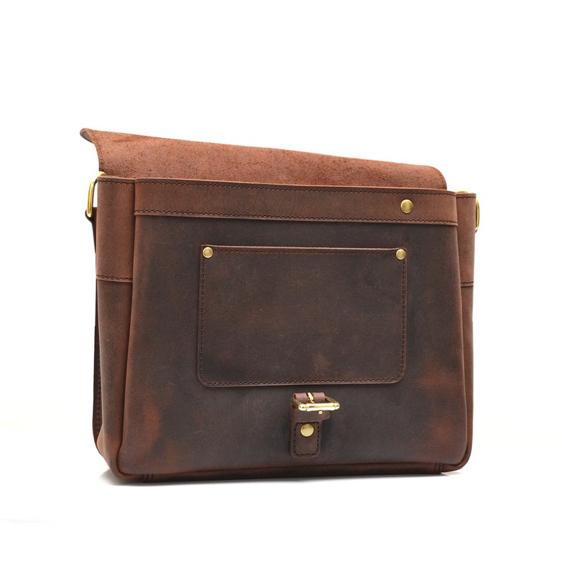 May include: A brown leather messenger bag with a flap closure and a front pocket. The bag features brass-coloured hardware, including a buckle and rivets. The leather has a distressed appearance.