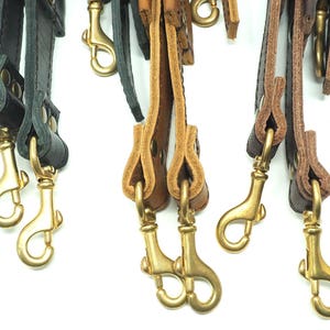 May include: Three sets of leather straps with brass clasps. The straps are in black, brown, and tan.