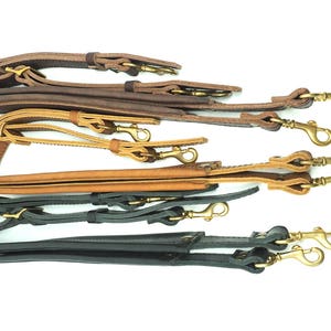 May include: Three leather straps with gold metal clasps. The straps are brown, tan, and black.