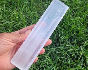 May include: A white selenite wand with a smooth, polished surface. The wand is approximately 6 inches long and has a rectangular shape.