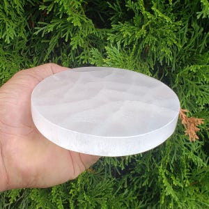 May include: A white selenite charging plate, a round disc of smooth, polished selenite crystal. The plate is approximately 15 cm in diameter.