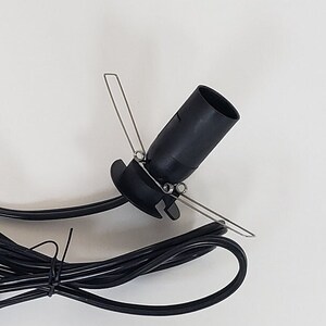 Pu&ograve; includere: Cavo elettrico nero con una presa per lampadina nera e tre clip metalliche. La presa &egrave; progettata per essere montata su una superficie.