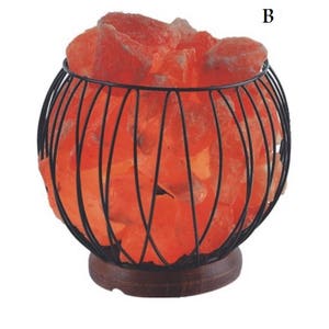 May include: A Himalayan salt lamp in a black wire cage with a wooden base. The salt crystals are glowing orange.