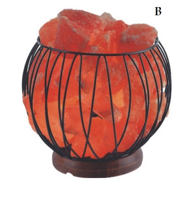 May include: A Himalayan salt lamp in a black wire cage with a wooden base. The salt crystals are glowing orange.