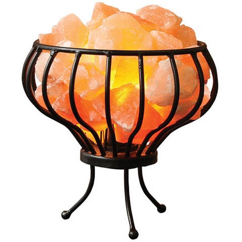 May include: A Himalayan salt lamp with a black metal cage base. The salt crystals are illuminated from within, creating a warm glow.