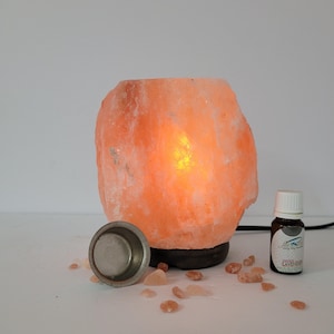May include: A Himalayan salt lamp with a warm orange glow, a small metal dish, and a bottle of essential oil labeled "Pure Essential Oil Lavender".