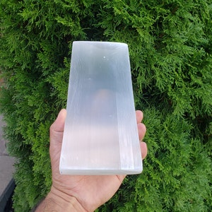 May include: A large, white selenite crystal slab with a smooth, polished surface. The crystal is rectangular in shape and has a natural, striated texture.