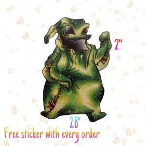May include: A sticker of a cartoon character with a green and yellow colour scheme, with a starry pattern. The sticker is 7.1 cm wide and 5.1 cm tall. The character has a stitched appearance and a sinister grin.