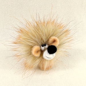 May include: A fluffy, brown and white stuffed animal with a black nose and large, black eyes. The animal has a spiky, shaggy mane.