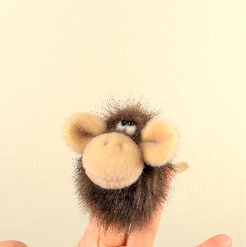 Puede incluir: Un t&iacute;tere de dedo marr&oacute;n y beige con una cara peluda y orejas grandes. El t&iacute;tere tiene ojos negros y una peque&ntilde;a nariz rosa.