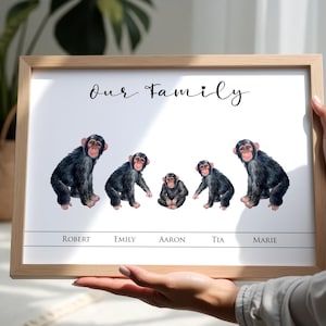 May include: A framed print with a watercolour illustration of five chimpanzees. The words "Our Family" are at the top, with names below each chimp. The frame is a light brown colour.