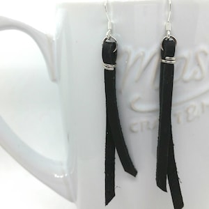 May include: A pair of black leather earrings with silver hooks and a silver wire wrap at the top.