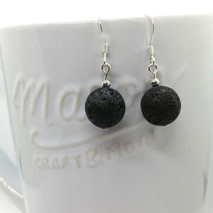 May include: A pair of silver earrings with black lava rock beads. The earrings are simple and elegant, and would make a great gift for any occasion.