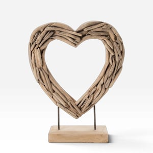 Peut inclure: Une sculpture en forme de cœur composée de nombreux morceaux de bois flotté brun clair. Le cœur est monté sur deux fines tiges métalliques sombres fixées à une base rectangulaire en bois clair, formant ainsi un objet de décoration stable.