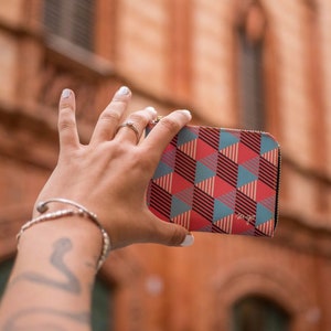 Peut inclure: Un portefeuille à motif géométrique rouge, bleu et noir avec le texte "so go" imprimé sur le devant.