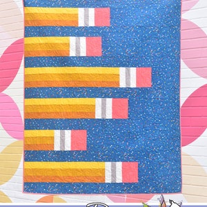 May include: A quilt with a blue background and a pattern of yellow, orange, pink, and gray pencils. The quilt is titled "Pointless" and is by Running Doe Quilts for Villa Rosa Designs.