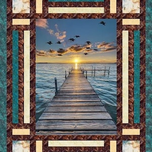 May include: A wooden dock extends into a lake at sunset, with a flock of birds flying overhead. The dock is framed by a decorative border with brown, beige, and teal stripes.