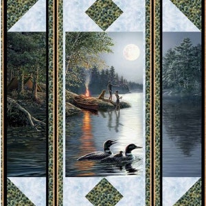 Puede incluir: Un bloque de colcha que presenta una escena nocturna con un lago, árboles, una fogata y dos personas pescando. El bloque también incluye un par de colimbos nadando en el lago. El bloque está enmarcado con un borde verde oscuro.