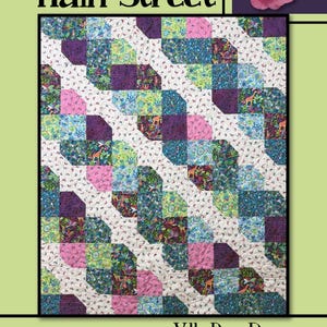 May include: A quilt pattern titled Main Street by Villa Rosa Designs featuring a repeating diagonal block design. The fabric squares display various patterns in shades of purple, pink, teal, and green, with small giraffe and butterfly motifs.