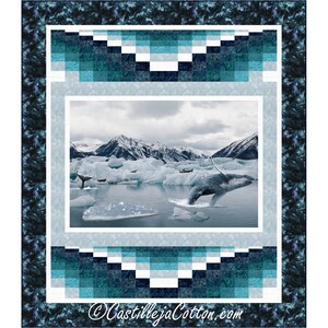 May include: A quilt pattern featuring a whale jumping out of the water in front of a snowy mountain range. The quilt is made with blue, white, and gray fabric. The quilt is framed with a dark blue border.