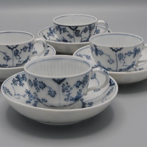 Puede incluir: Juego de cuatro tazas de té y platillos de porcelana azul y blanca con un patrón floral.