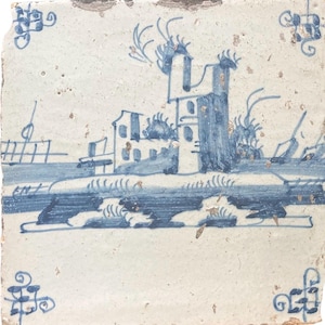 Op de afbeelding: Een handgeschilderde keramische tegel in blauw en wit, die een landschap met een gebouw en bomen voorstelt. De tegel heeft een witte achtergrond met blauwe details. De tegel is versierd met een eenvoudig ontwerp van een gebouw met een toren en bomen. De tegel is omgeven door een blauwe en witte rand.